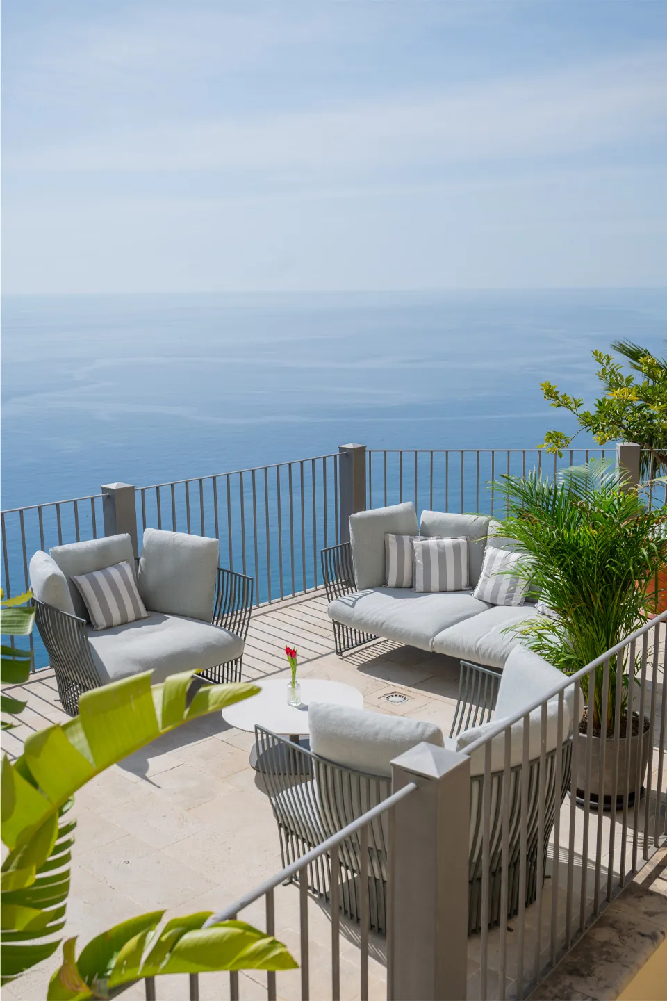 Terrazza del Bellevue Restaurant Hotel Metropole Taormina: salotto outdoor con divani grigi, piante tropicali e vista sul mare Ionio