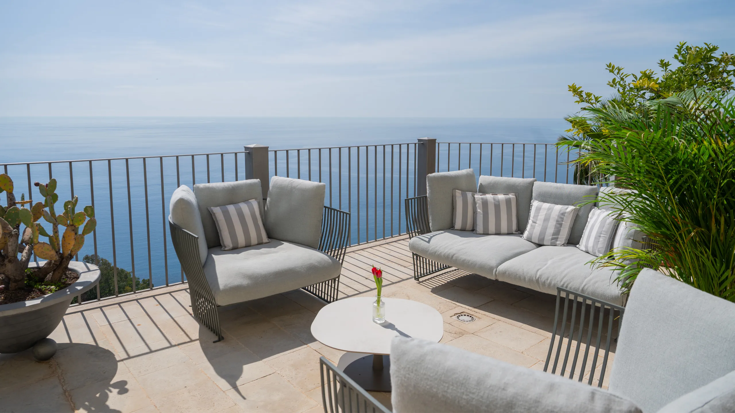 Terrazza del Bellevue Restaurant all'Hotel Metropole Taormina: salotto outdoor con divani grigi, cactus e vista panoramica sul mare Ionio