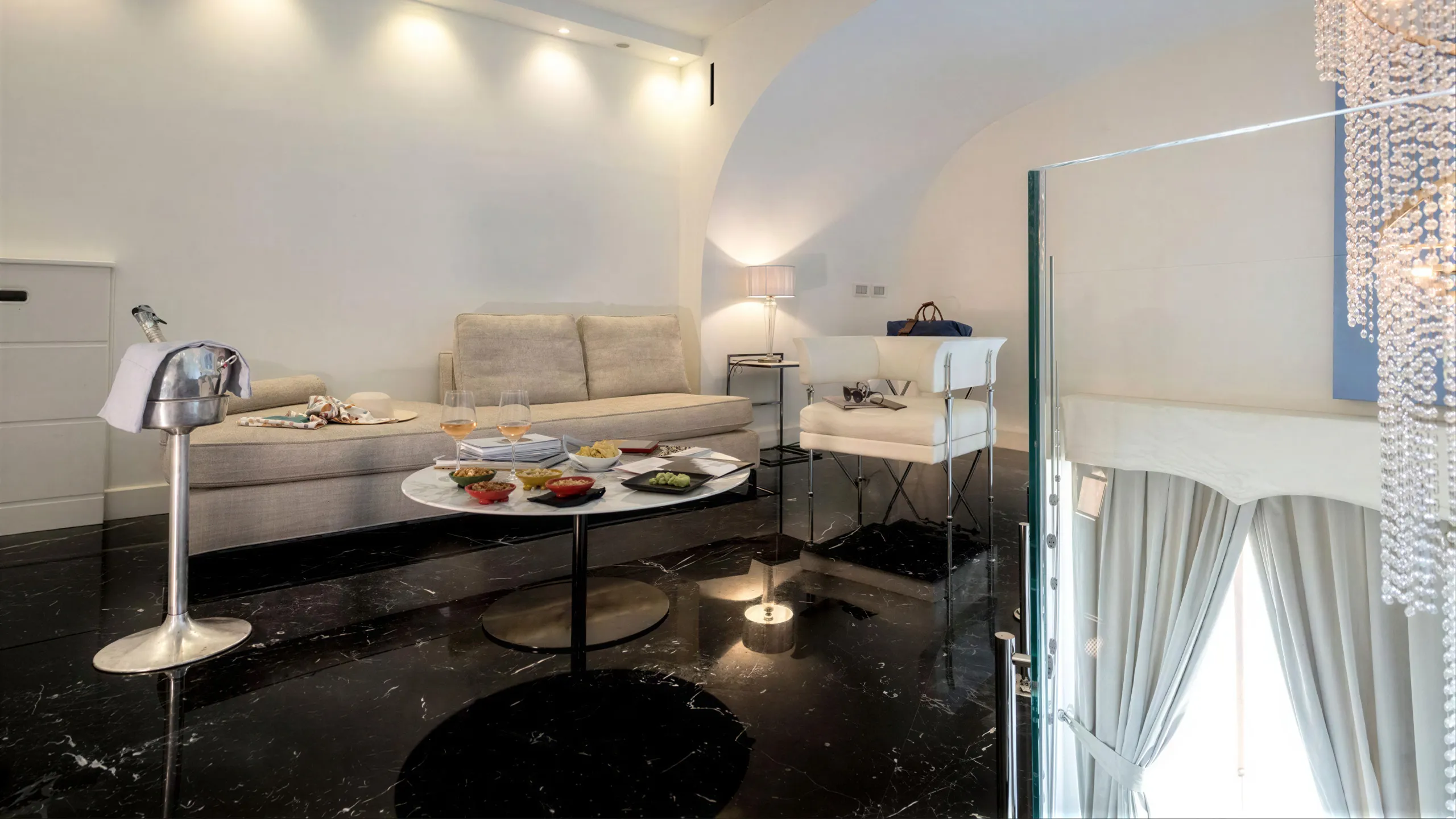 Sea View Suite: living room with barrel vault, beige sofa, black marble floor and champagne on the coffee table