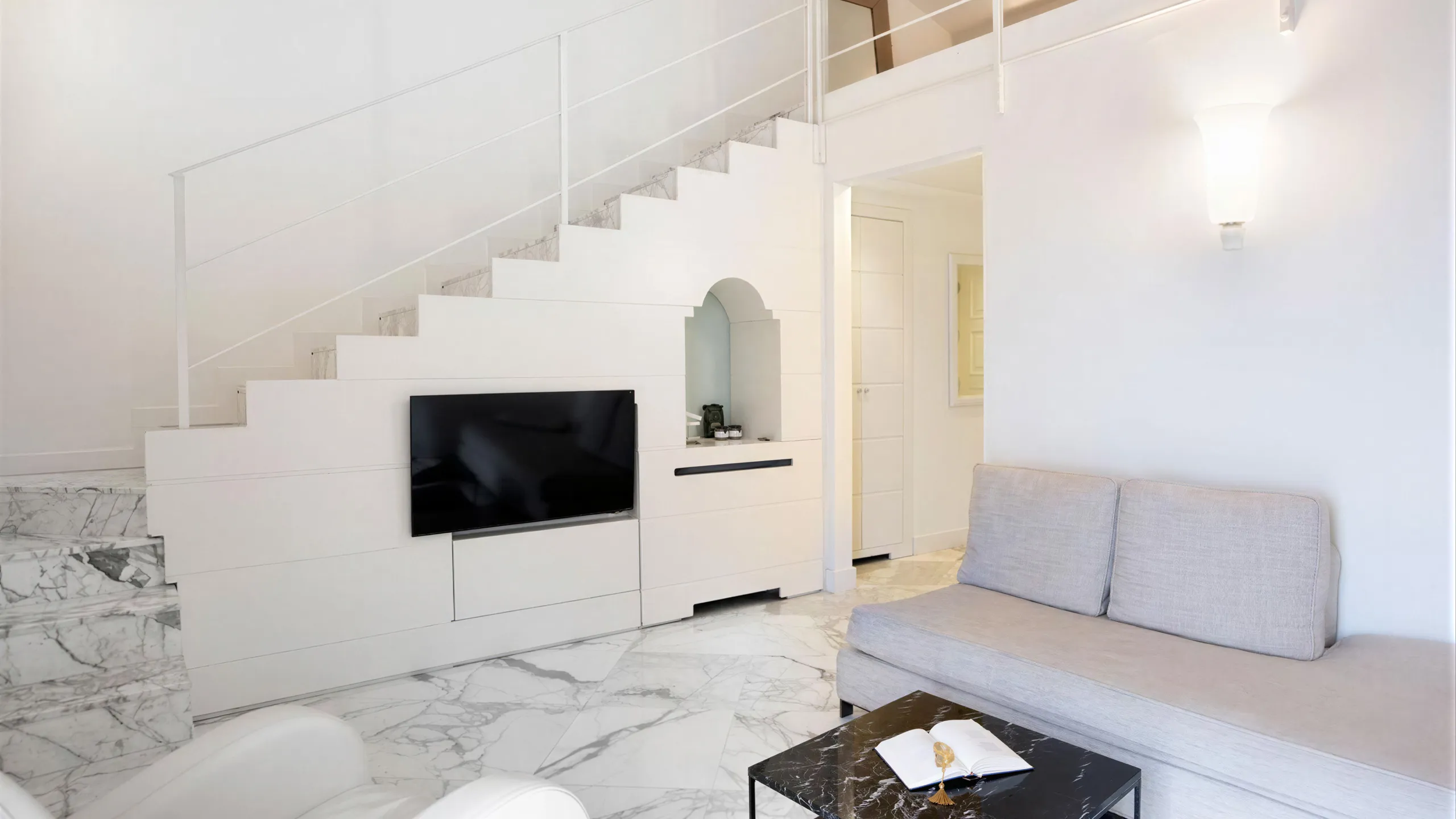 Two-level Sea View Suite: living room with grey sofa, white marble staircase, TV and marble floor