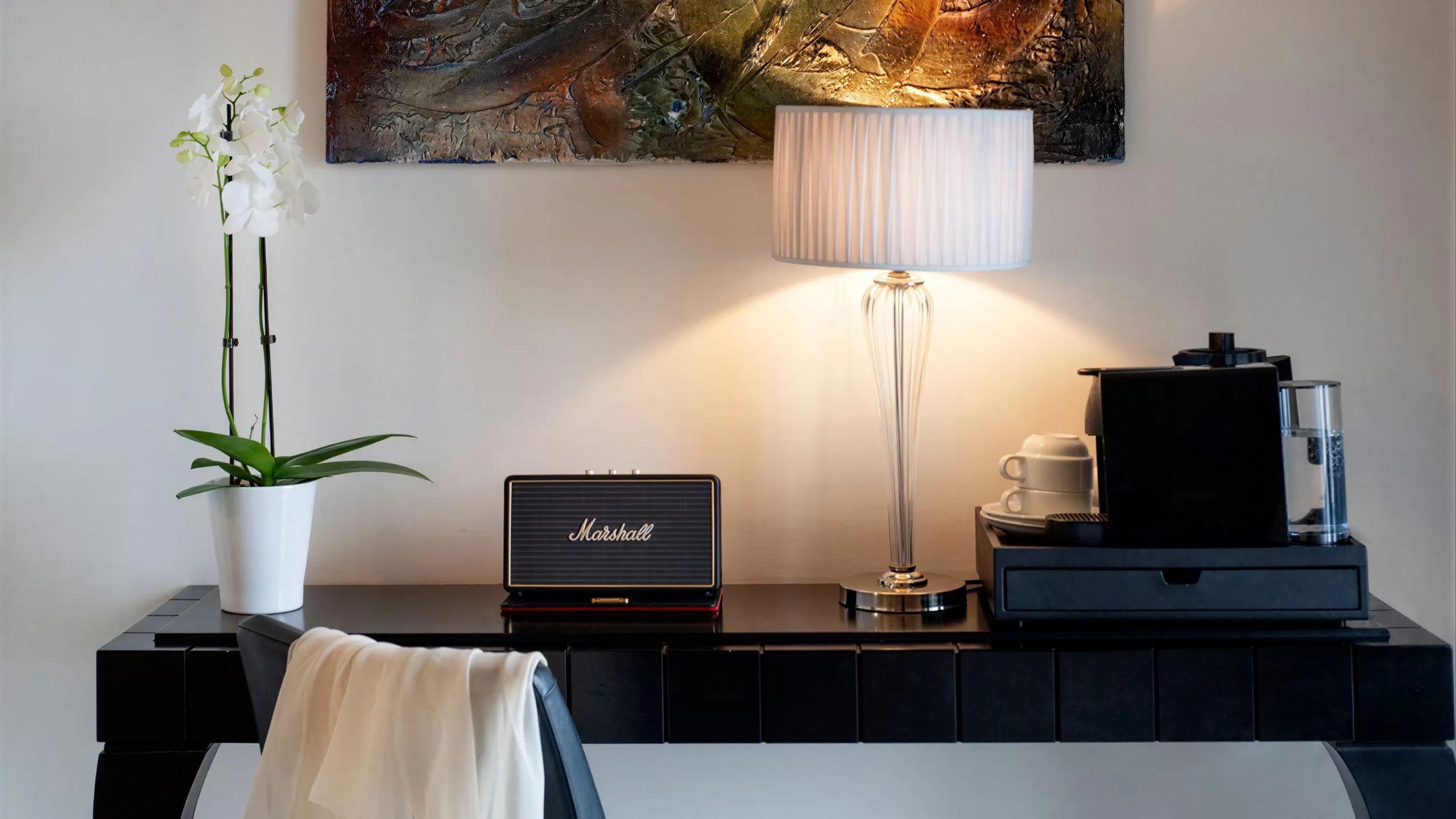 Sea View Suite detail: desk with Marshall speaker, coffee machine, white orchid and contemporary artwork