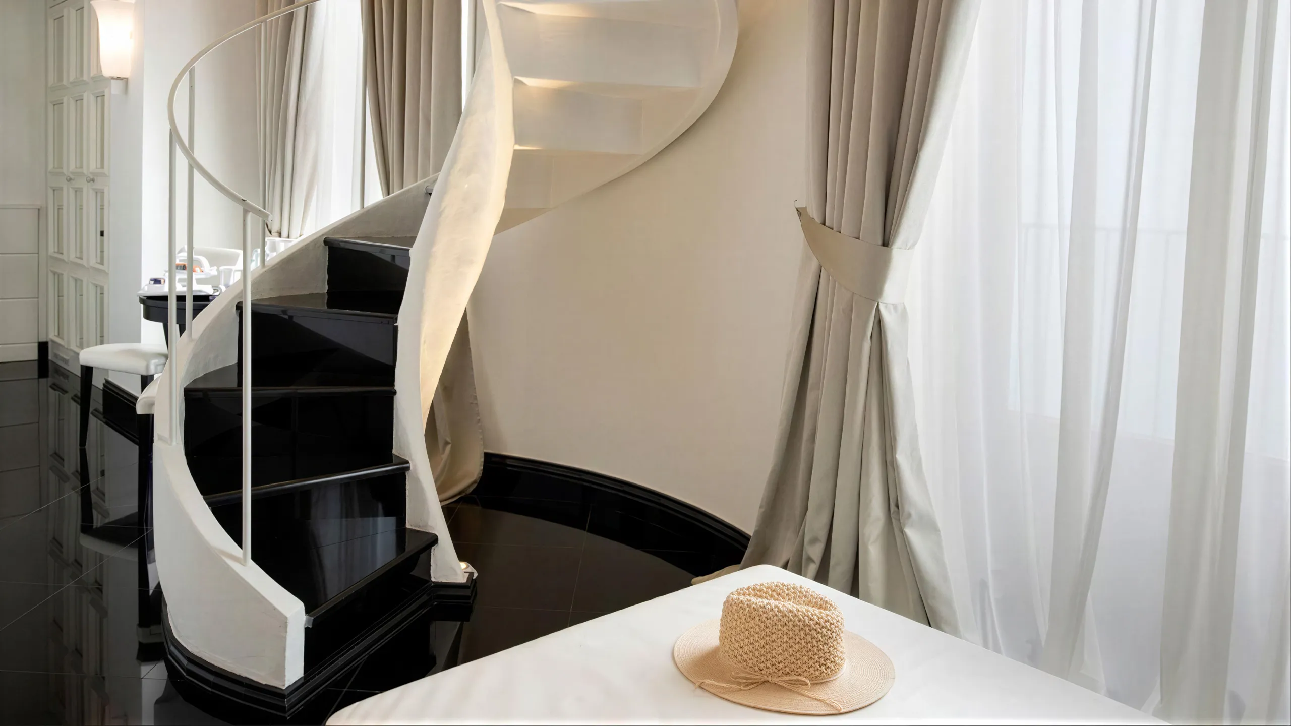 Sea View Suite: elegant black and white spiral staircase, black marble floor and straw hat on the bed