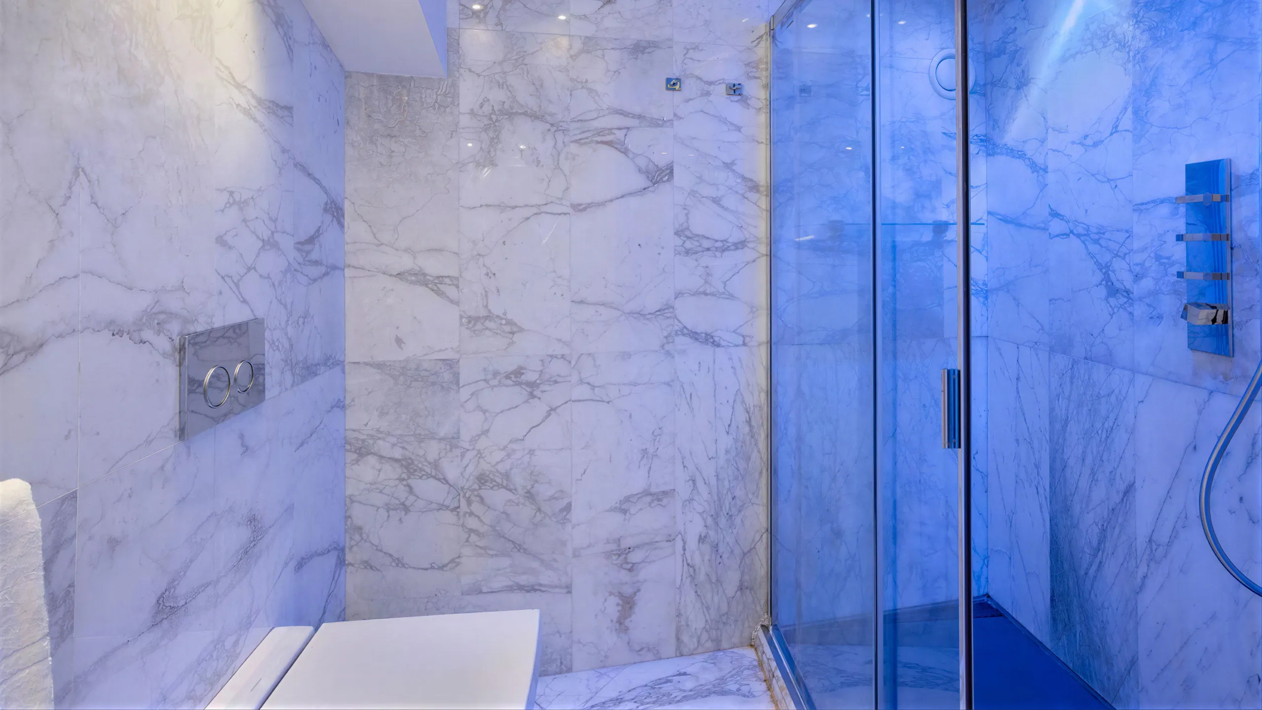 Sea View Suite bathroom: white Carrara marble cladding, shower with blue LED lighting and chrome fittings