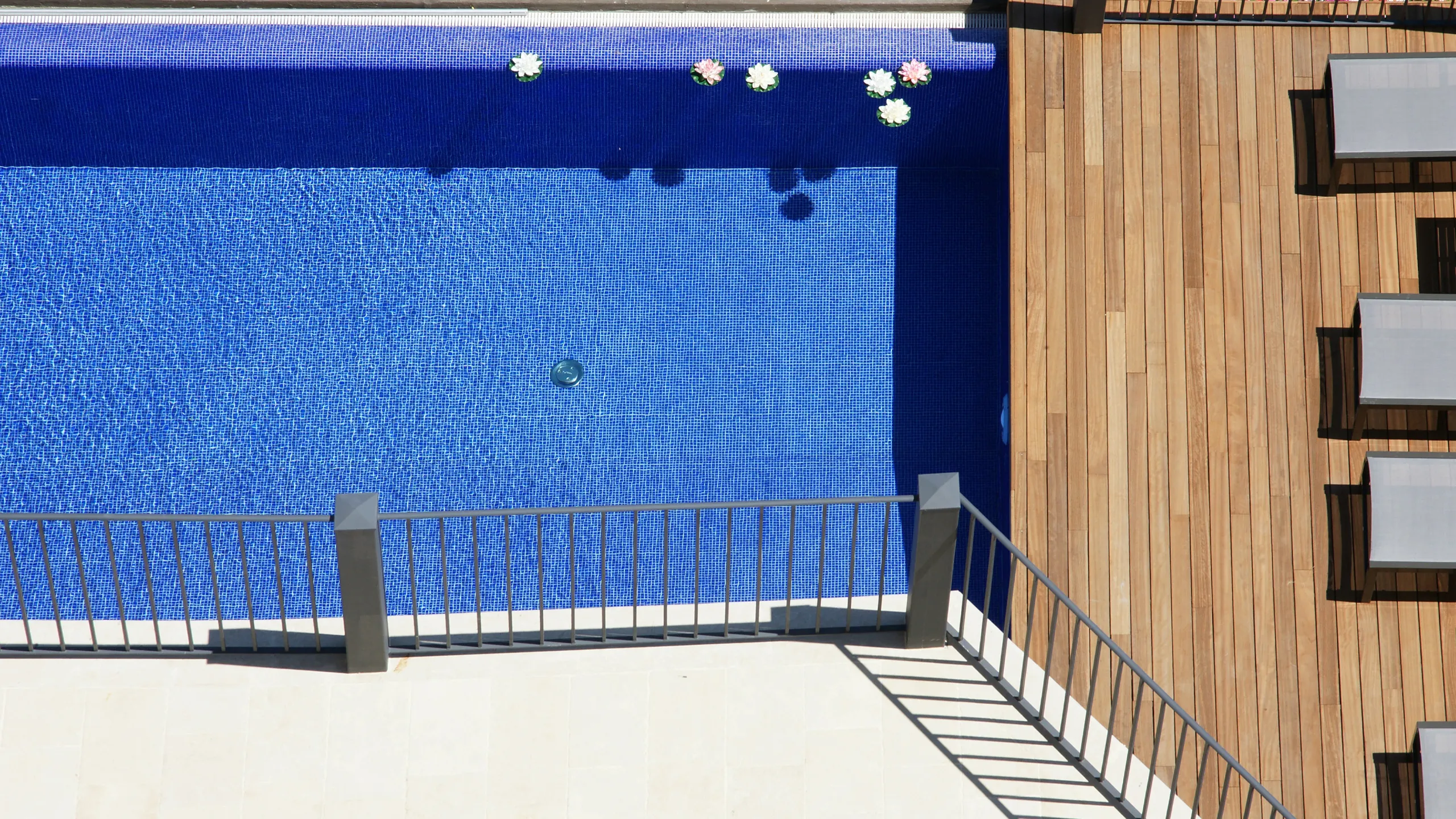 The Met Pool Bar Hotel Metropole Taormina: vista dall'alto della piscina a mosaico blu con fiori galleggianti e deck in legno